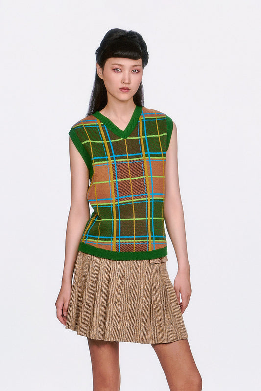 Woman wearing a Plaid Sweater Vest - Leaf Green top and beige pleated skirt